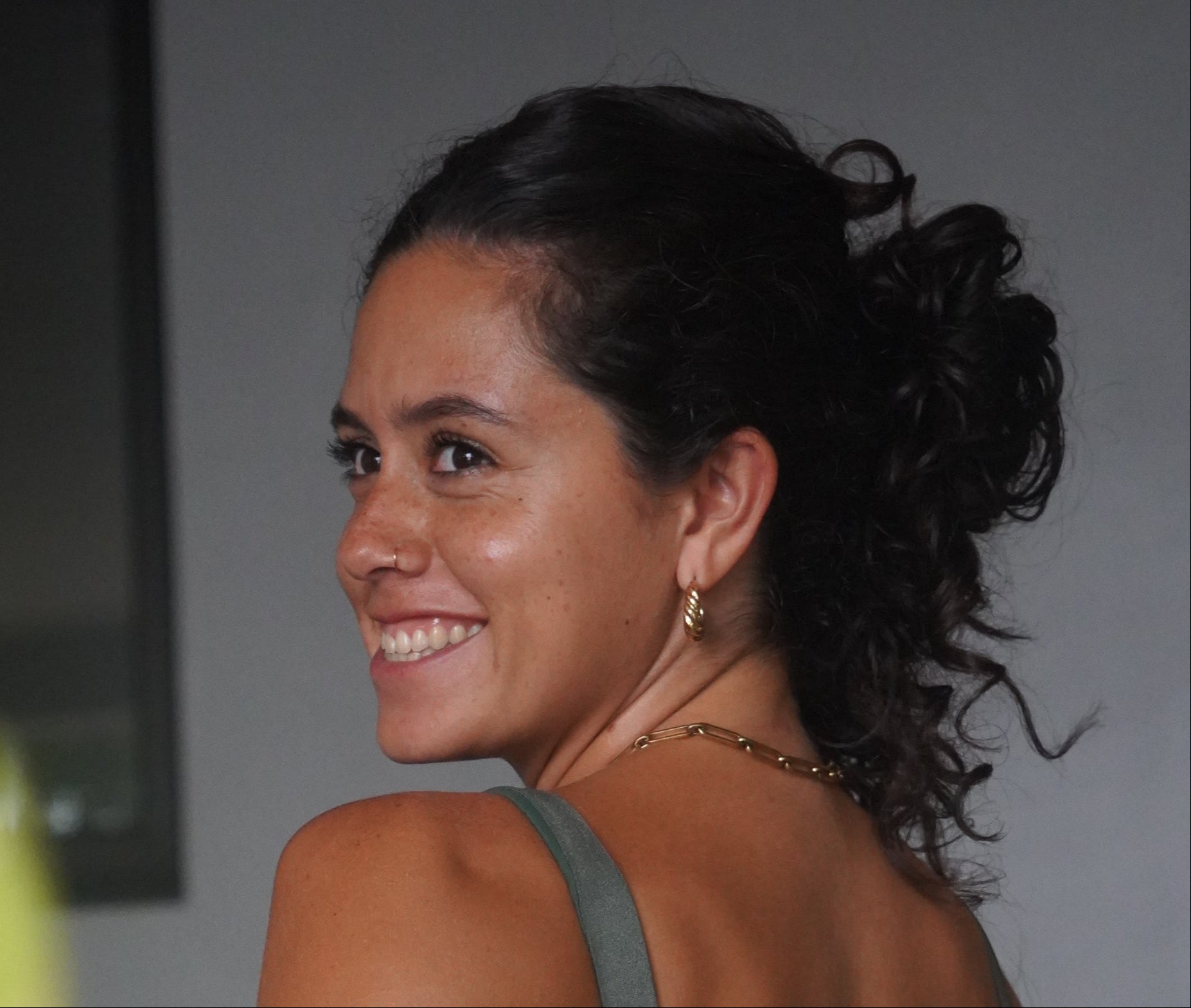 Woman with styled hair smiling against a neutral background